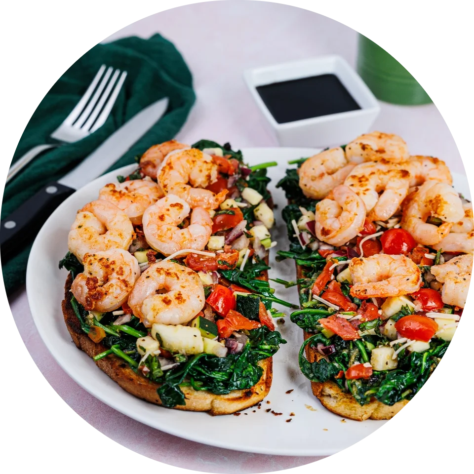 Sautéed shrimp and spinach bruschetta on toasted bread with cherry tomatoes