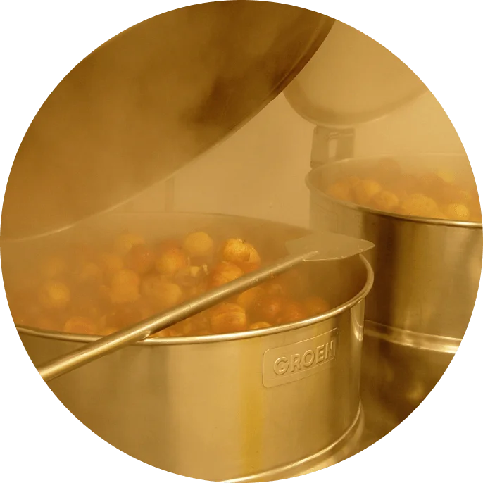 Close-up of golden-colored snack balls being prepared in brass commercial pots, representing food production