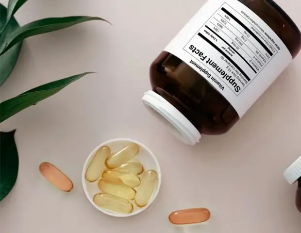 Supplement bottle with Supplement Facts label tipped over with capsules and softgels spilling out