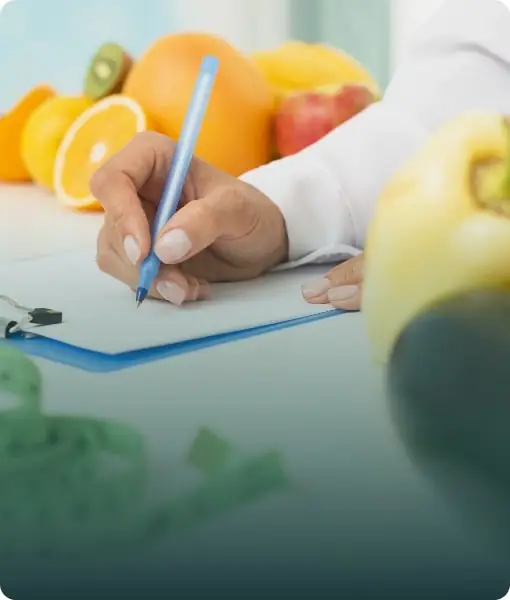 A student writing notes on a clipboard with fresh fruit, representing nutrition and dietetics programs.